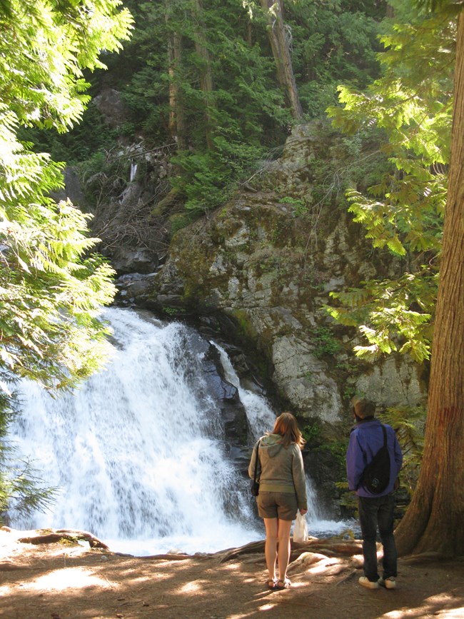 Park visitors pause to listen to the sounds of a waterfall in North Cascades National Park, Washington