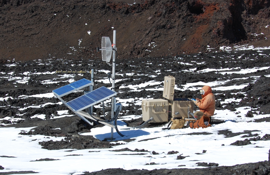 Photo of a person sitting with monitoring instruments on a snowy mountainside.