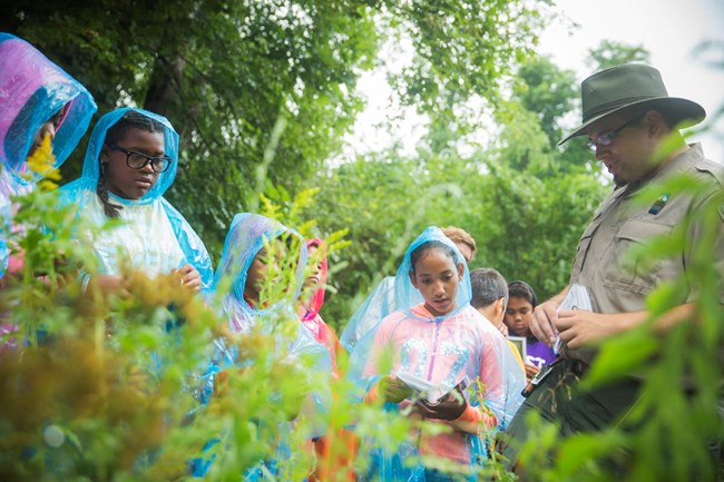 boys and girls club members in rain coats with park ranger.