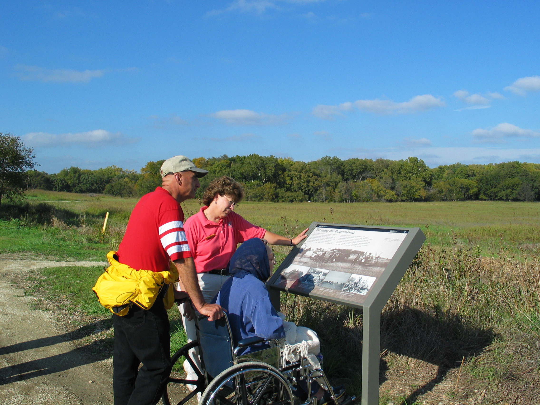 Three visitors viewing wayside along Bottomland Nature Trail