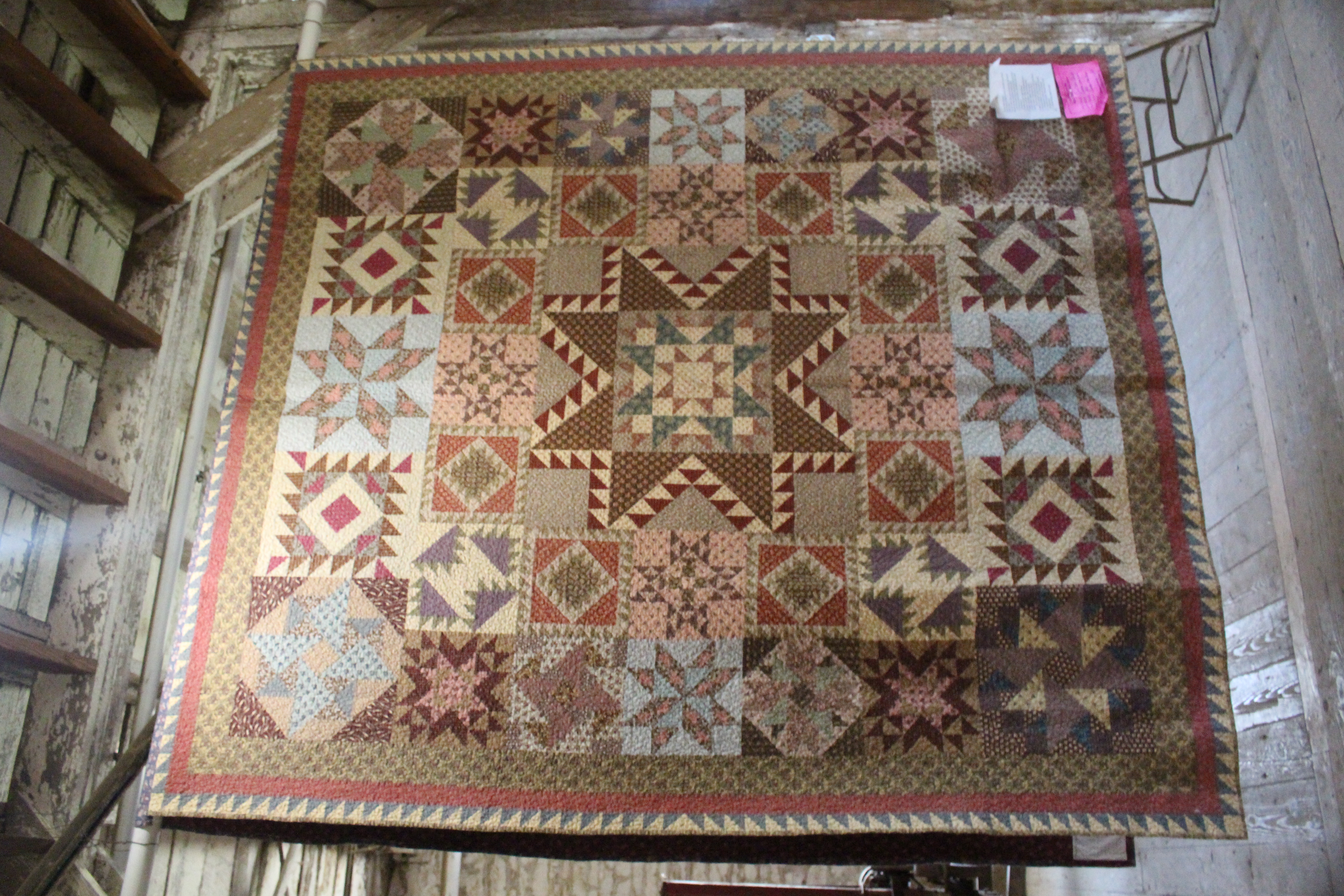 Large quilt depicting twelve battles of the American Civil War. Colors of tan, brown, dark red, light blue and many triangles and squares make up the design.