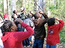 A ranger points out a bird to students with binoculars