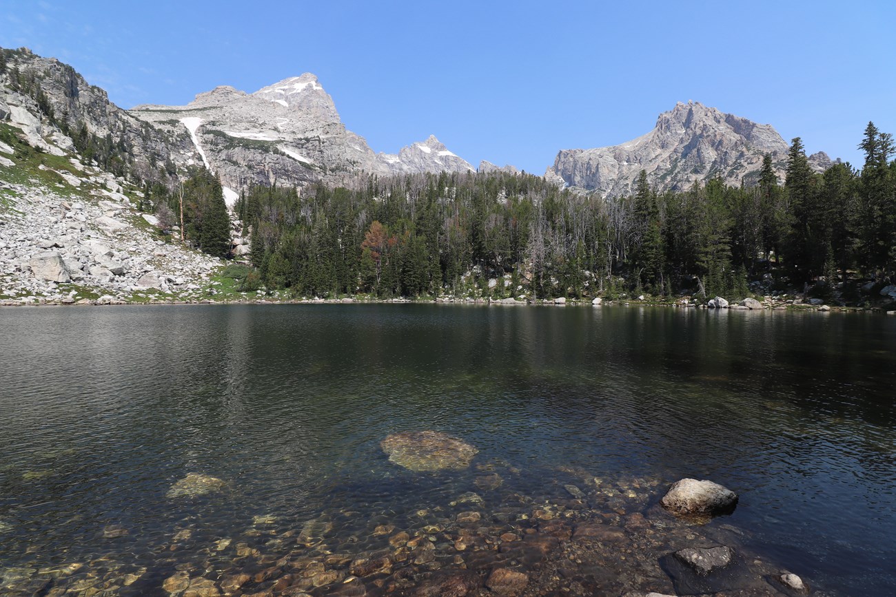 An alpine lake sits beneath rocky mountain peaks.