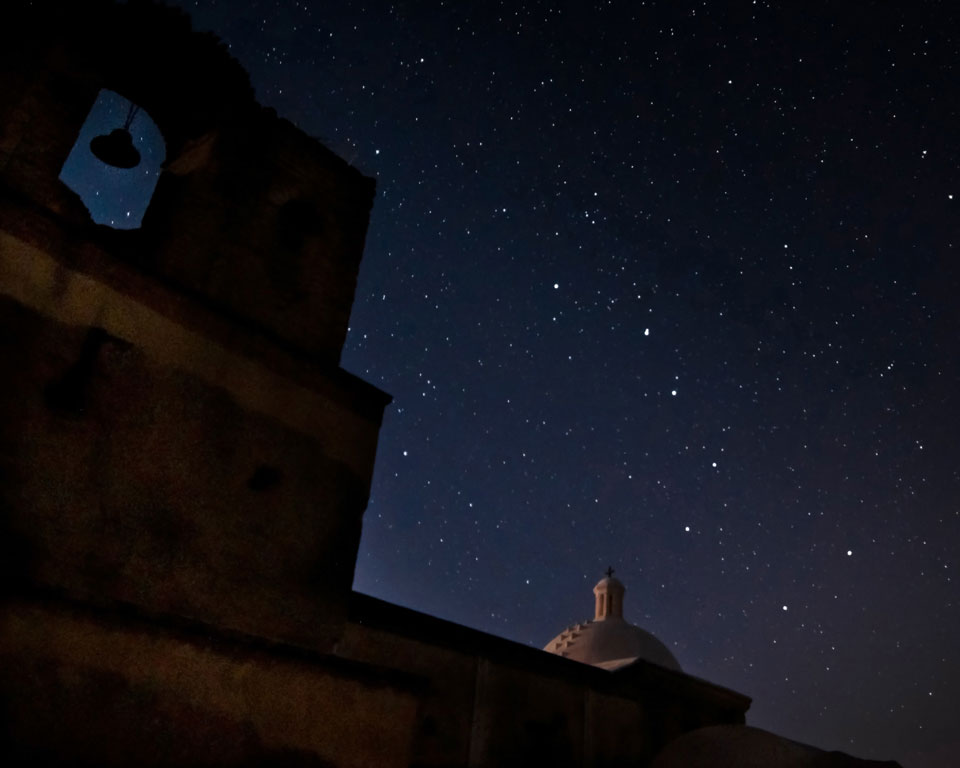 stars in night sky above church dome and bell tower