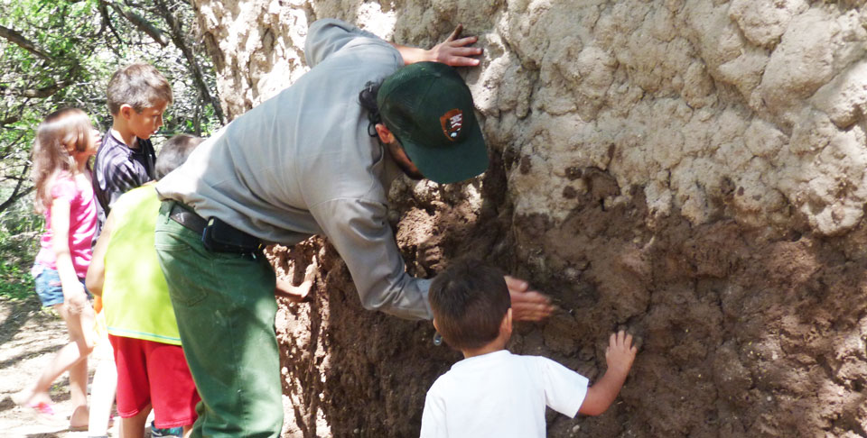 kids and ranger slapping mud on walls of mud house