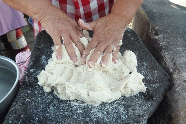 Corn tortillas-mixing Mixing corn masa on a stone metate.