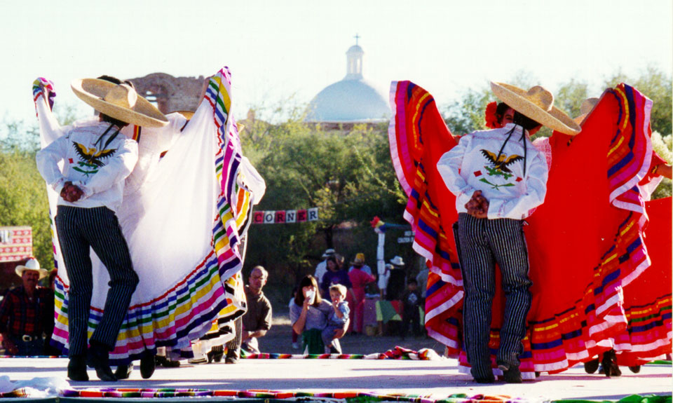 folklorico dancers on stage in front of church dome