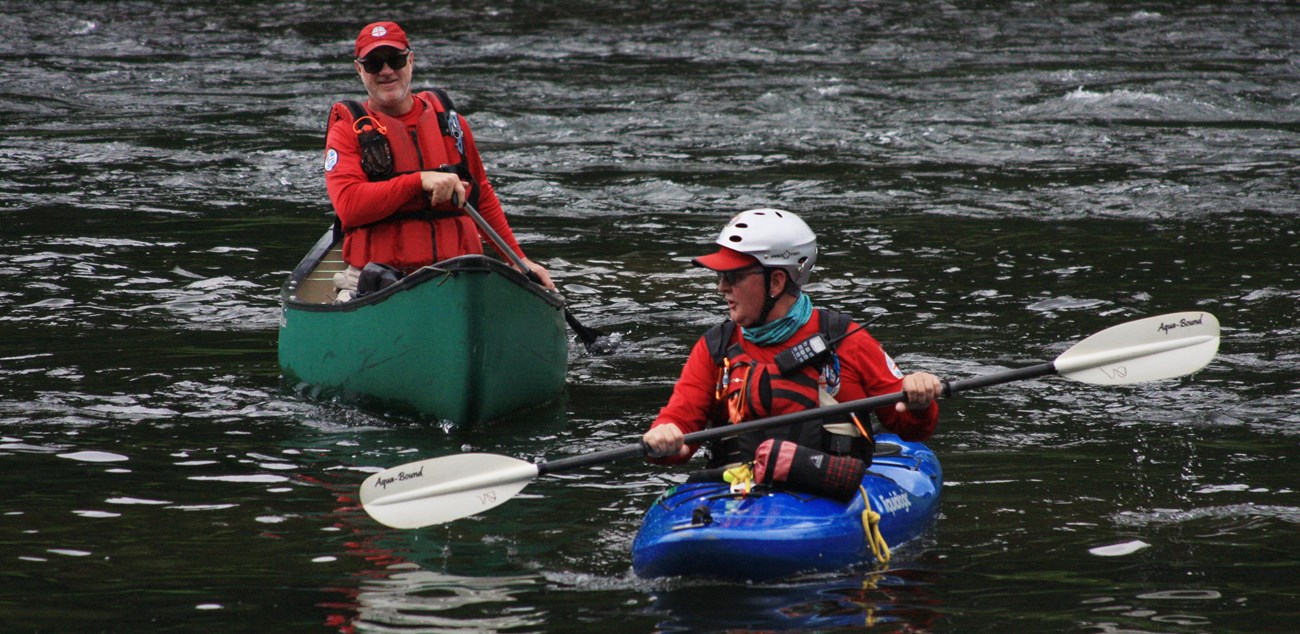 two national canoe safety patrol volunteers paddle in kayaks on water