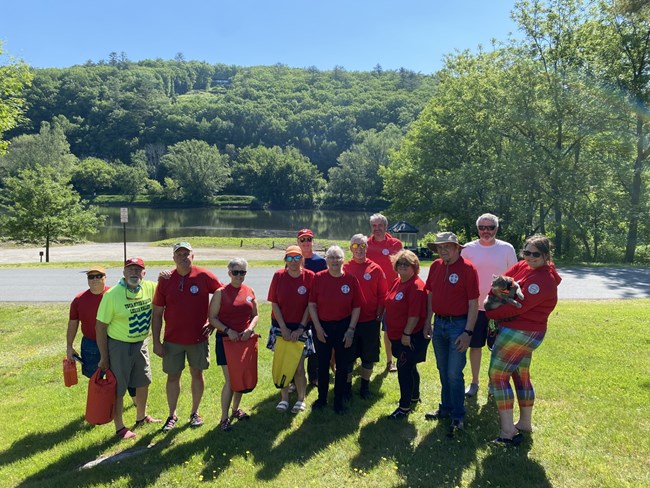 Group of National Canoe Safety Patrol volunteers in red NCSP shirts standing in front of river