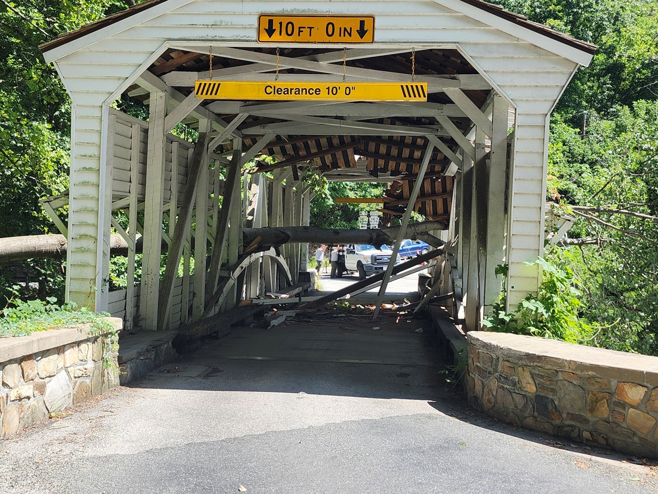 a tree fallen through the roof blocks the roadway through a covered bridge