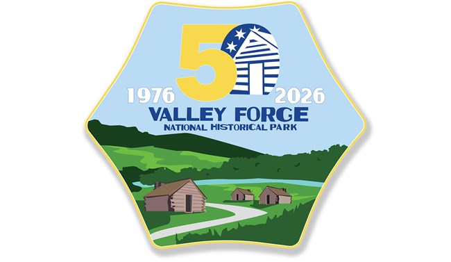 A hexagon shape containing the number 50 and years 1976, 2026. A log hut is inside the 0 of 50. a landscape with huts, a path, river, fields, and trees.