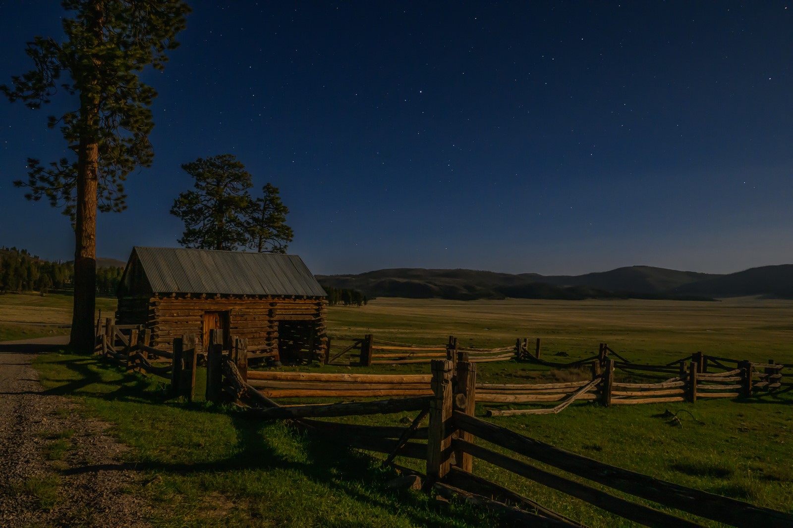 A historic, wooden barn overlooking a large valley at night.
