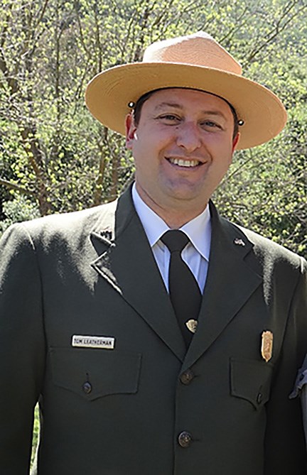 A man in a ranger hat and uniform smiles at the camera.