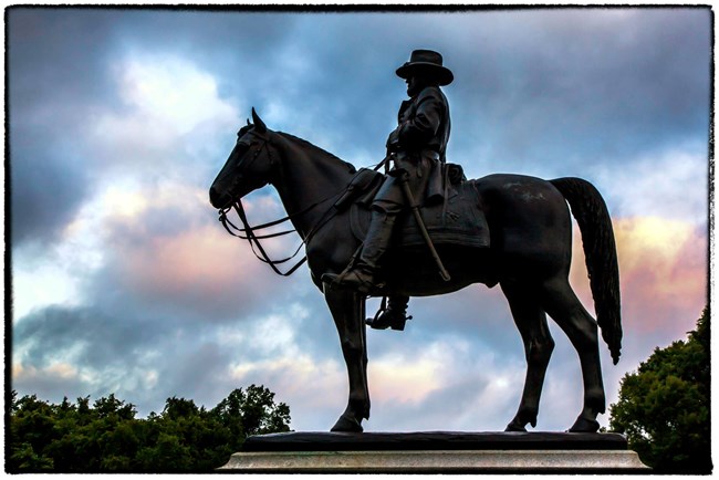The sun sets over the silhouette of general grant on horseback