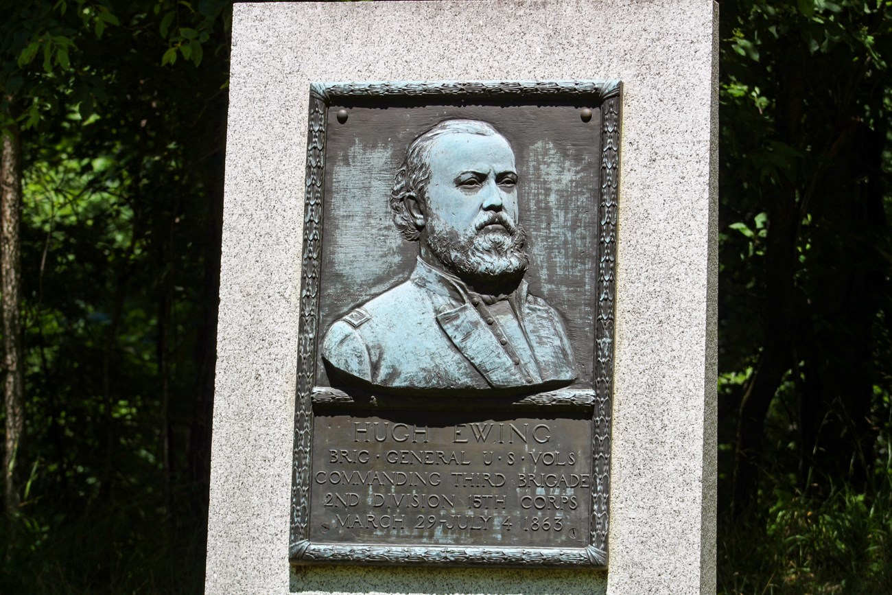 A bronze Relief of a man in uniform. Underneath the portrait is a small plaque with an inscription