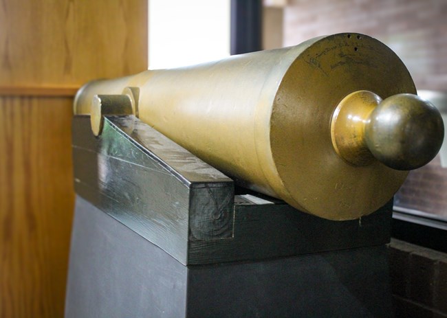 A gold painted cannon sits on a display stand in the Visitor Center