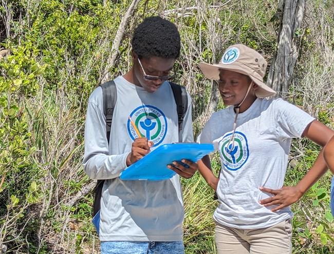 Image of two youths looking at a clipboard and smiling.