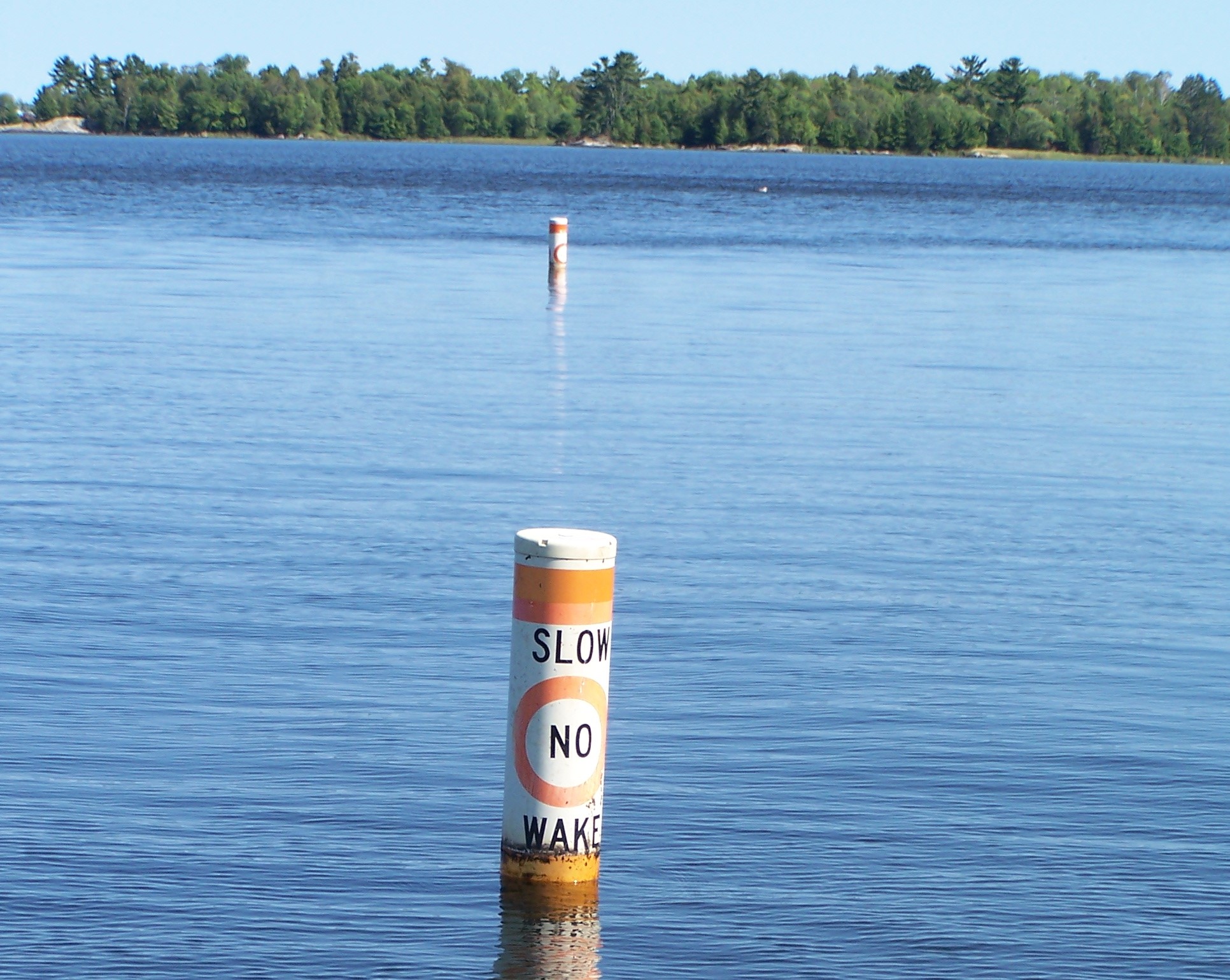 Orange and white No Wake buoys protrude from a lake surface