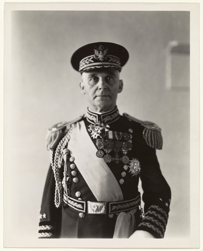 111-SC-099224_001 A mature white man in resplendent military garb with cords, sash, and medals.
