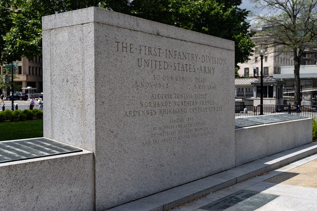 WHHO_Monuments_20250515_NKing_025 A rectangular stone monument flanked by a low, angled stone wall with bronze plaques on top.