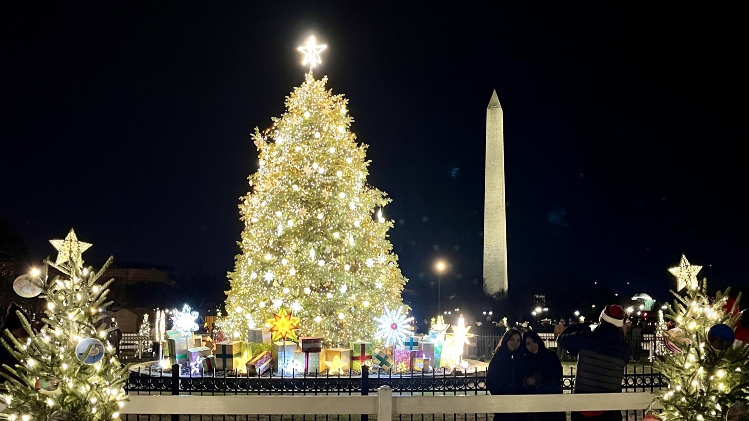 National Christmas Tree (2022) A nighttime scene with a large Christmas tree with white lights and a star on top in front of the Washington Monument.