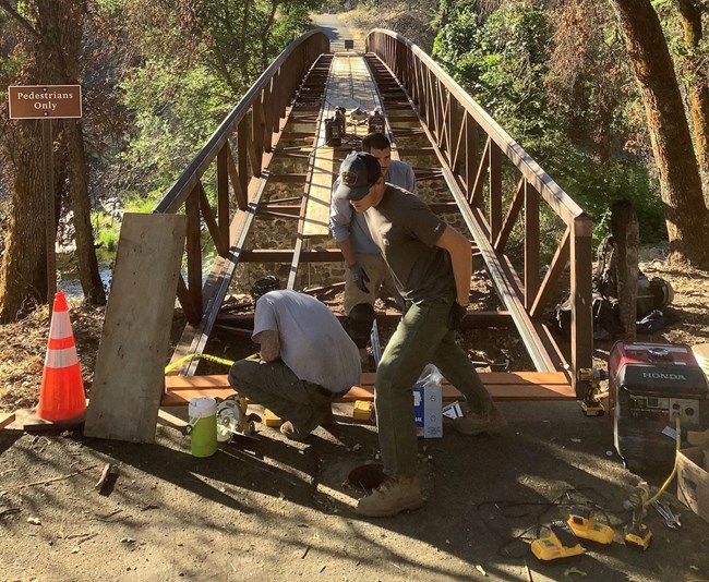 Park maintenance staff rebuilding the main footbridge within Tower House Historic District.
