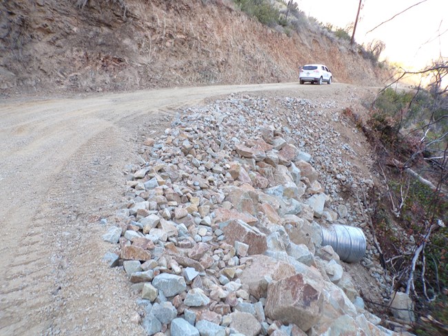 A park gravel roadway showing new culvert and rip rap treatment.