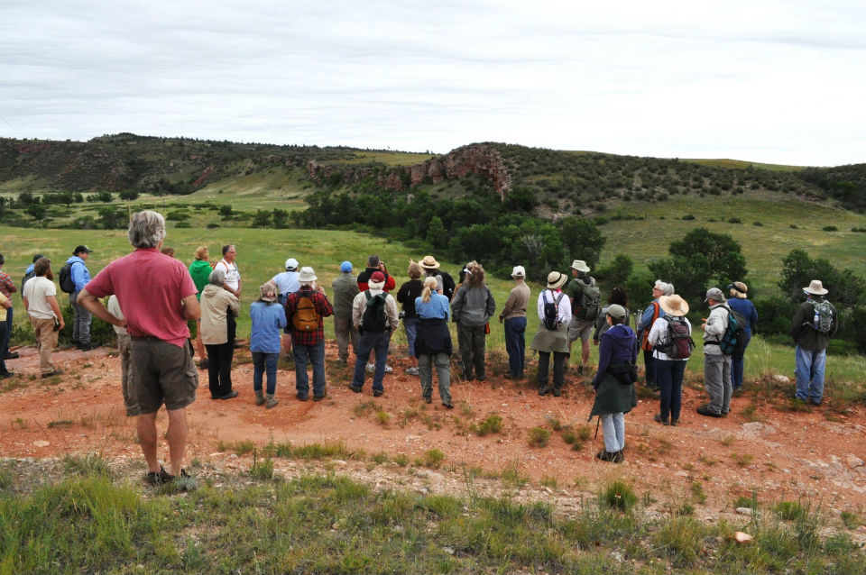 Ranger standing in front of a group of people looking at cliff in the background.