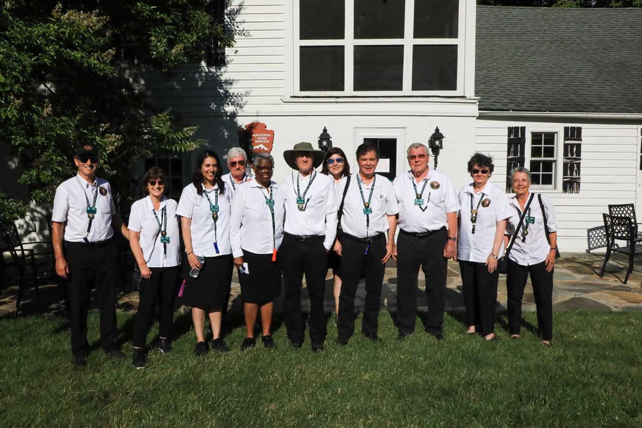 Group of volunteers wearing white dress shirts posing in front of a white home.