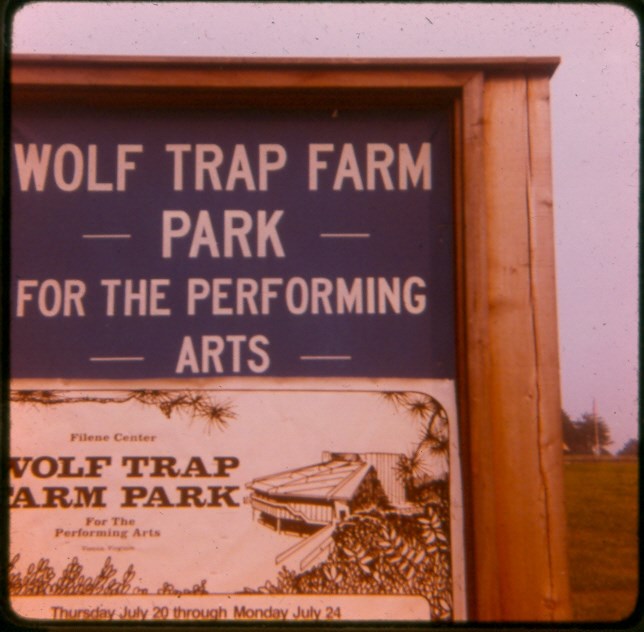 Scanned film slide of a purple sign reading "Wolf Trap Farm Park for the Performing Arts" placed above a white sign reading " Filene Center Wolf Trap Farm Park for the Performing Arts" and "Thursday July 20 through Monday July 24".