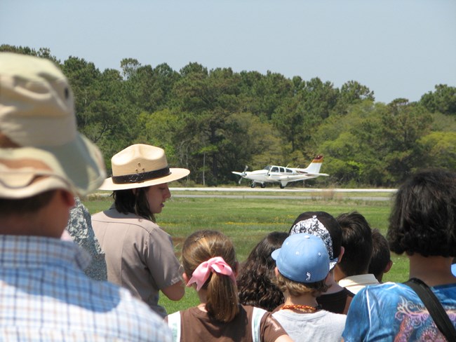 View of students as they look at a plane. Ranger is seen turning and talking to student.
