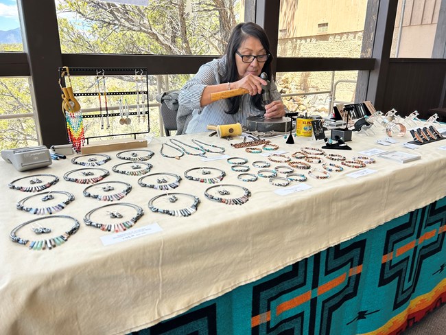 Diné silversmith Rosabelle Teesyatoh Shepherd works on a piece of jewelry at Walnut Canyon during a cultural demonstration event.