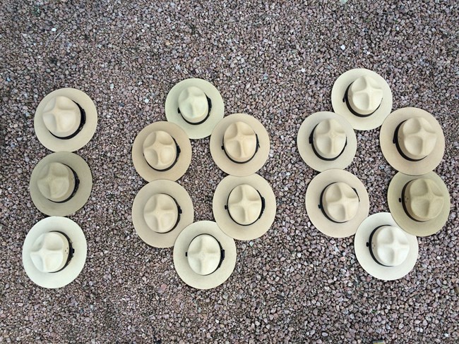 Park Ranger flat hats on the ground in the shape of number 100.