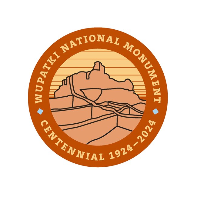 A round orange scale color graphic with the outline of Wupatki Pueblo and text encircling it reading Wupatki National Monument Centennial 1924-2024.