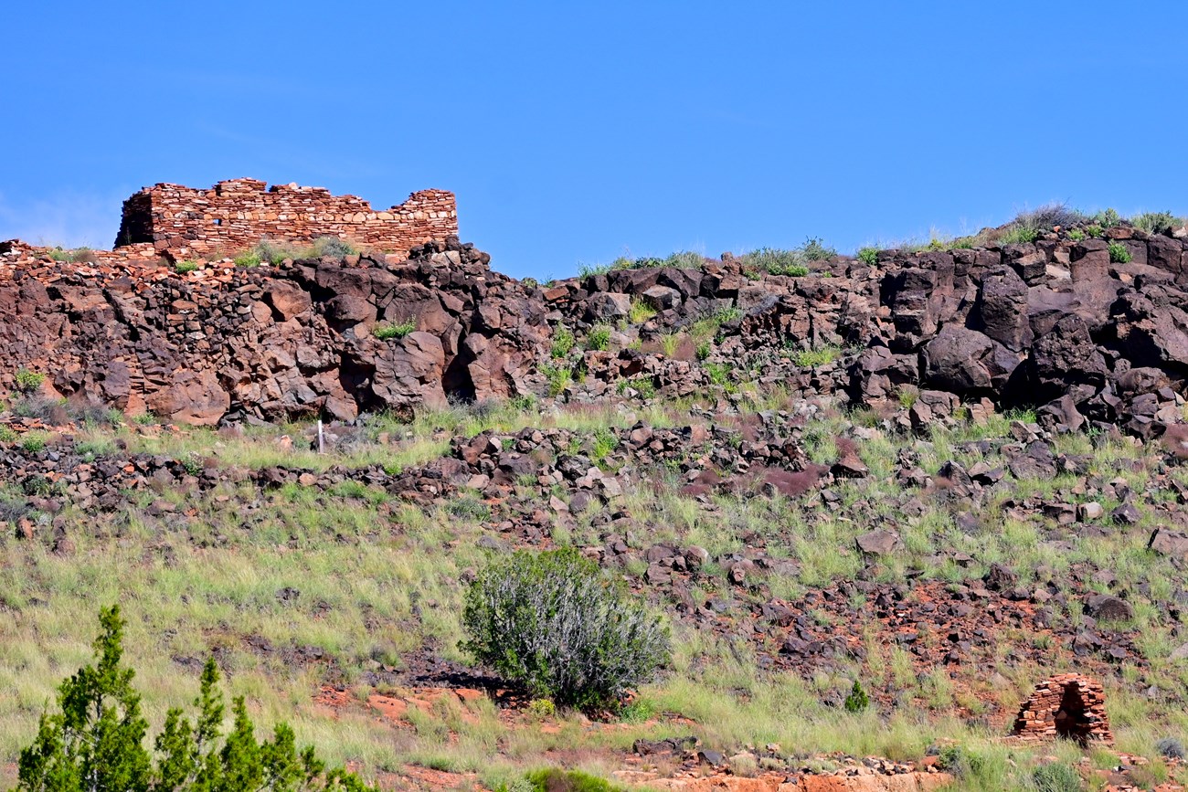 Remains of a sandstone pueblo sit atop a bluff in a desert landscape