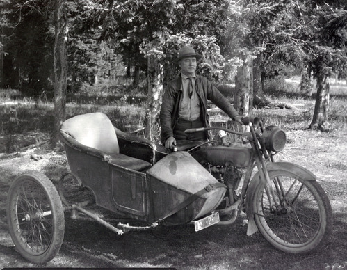 YELL36861 Image of a man standing next to a motorcycle and side car.