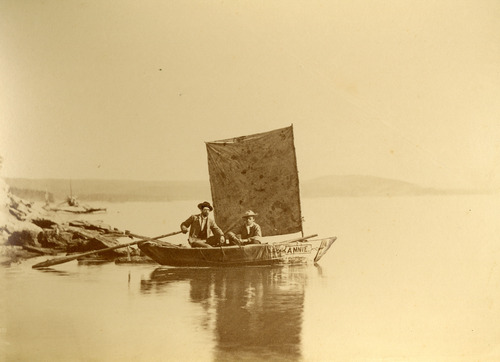 YELL50375 Image of two men in a small sail boat on a large lake.