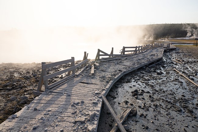Segment of damaged boardwalk covered with rocks and debris