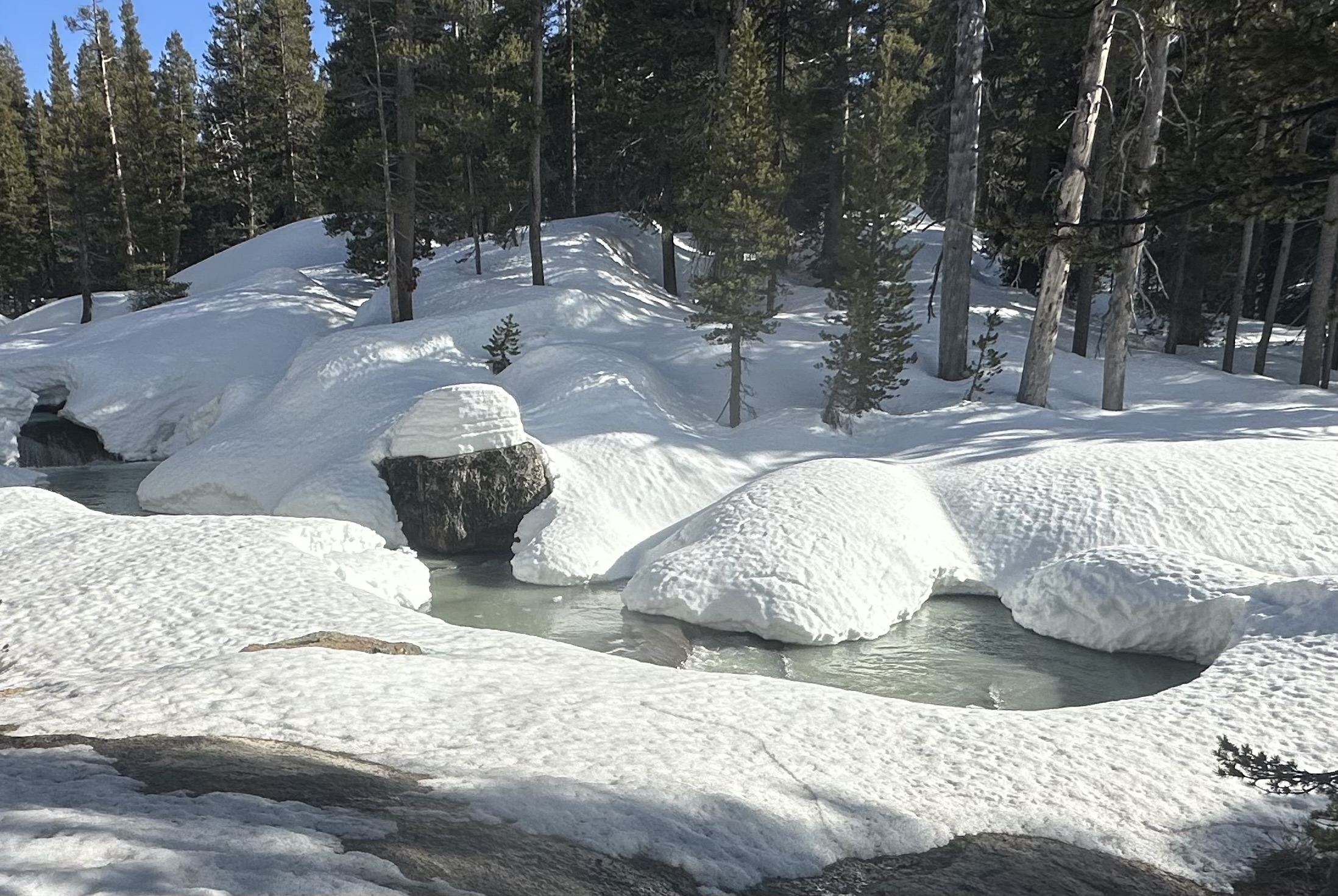 Billowy snow surrounds a grayish creek
