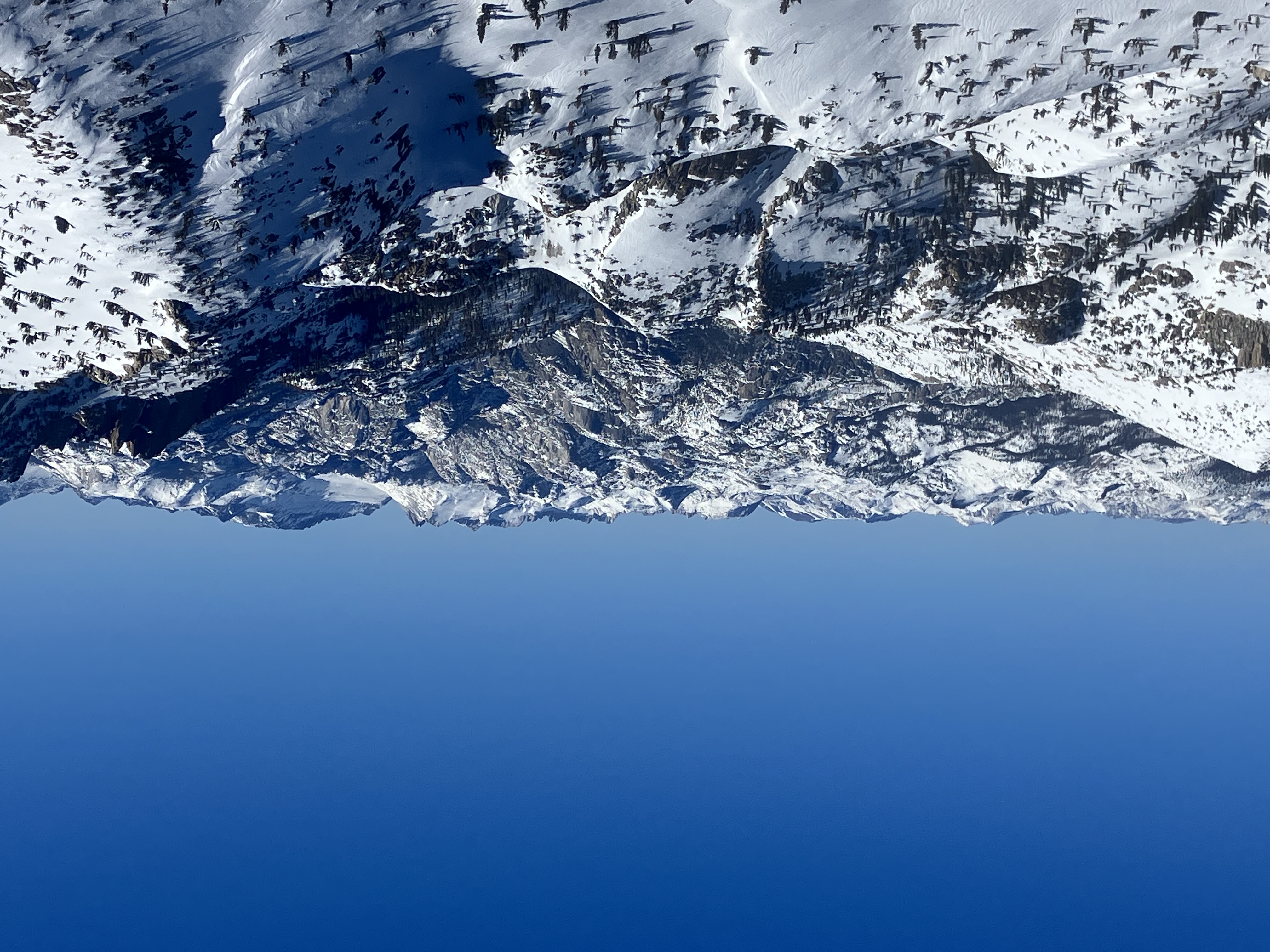 View beyond a granite canyon to various peaks and sawtooth ridge, all mostly covered in snow