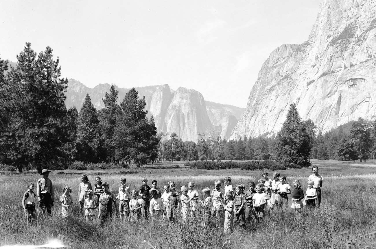 Ranger Walter Heil and a 1938 Yosemite Junior Nature School group explore Sentinel Meadow in the Valley.