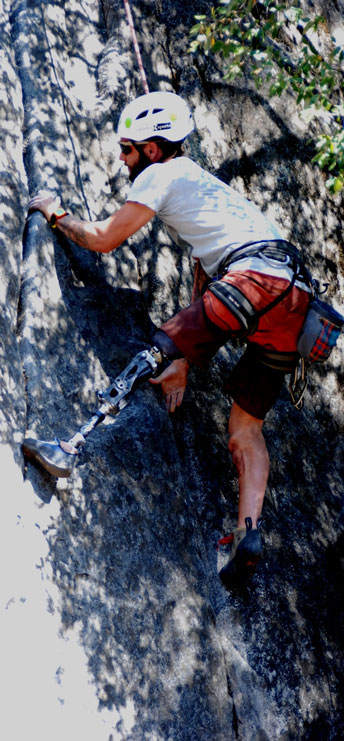 Rock climber with prosthetic leg climbing a cliff