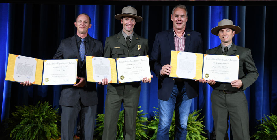 Three rangers and the Interior secretary on stage displaying award certificates