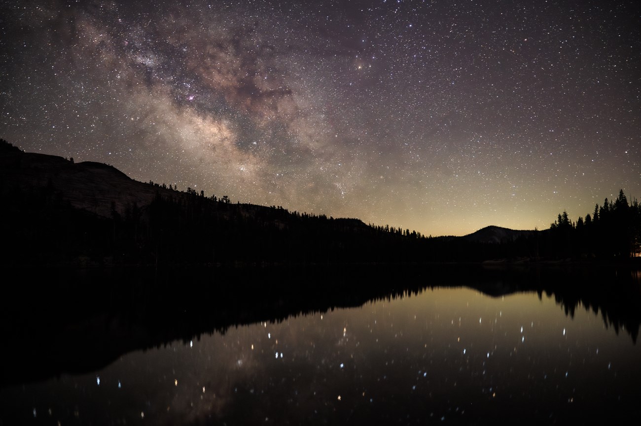 A stary sky and the Milky Way over a still mountain lake.