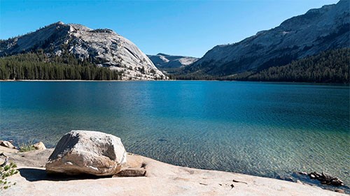 Tenaya Lake with granite boulder in foreground and granite domes in background