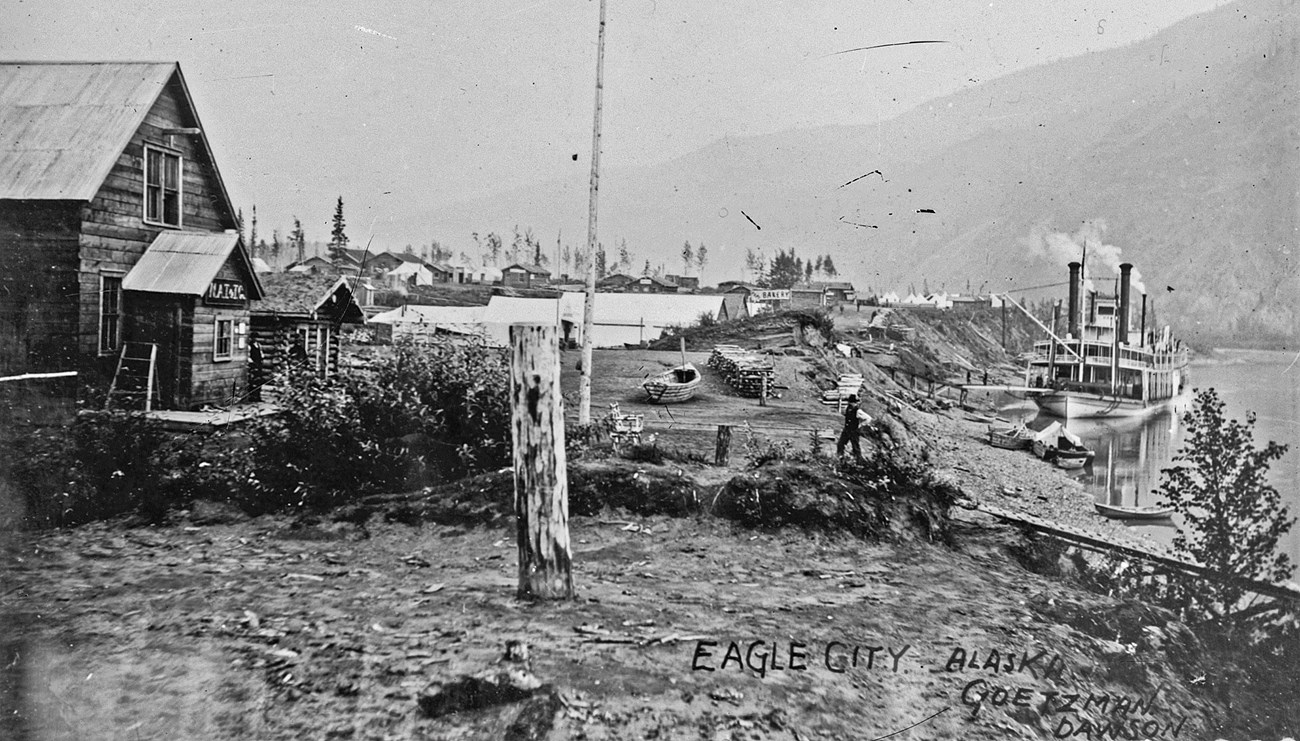 A paddlewheel steamboat docks at Eagle City, 1899. The photograph was taken by Henry J. Goetzman who had a photography shop in Dawson City.