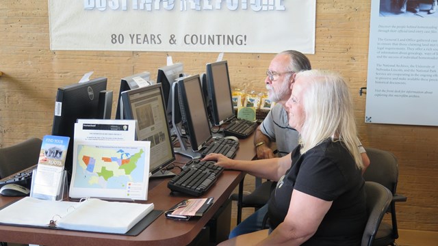 Two people sitting at computers looking at homestead records