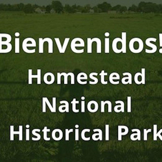 Person standing next to Homestead National Monument of America building sign