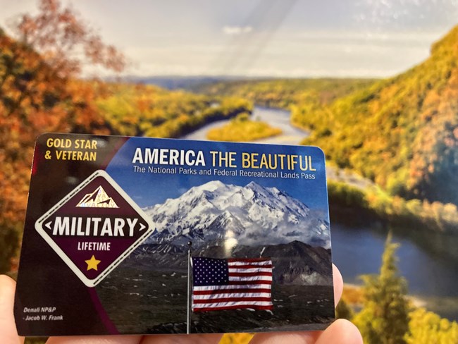 A military lifetime ATB pass in front of an image of the Delaware Water Gap.